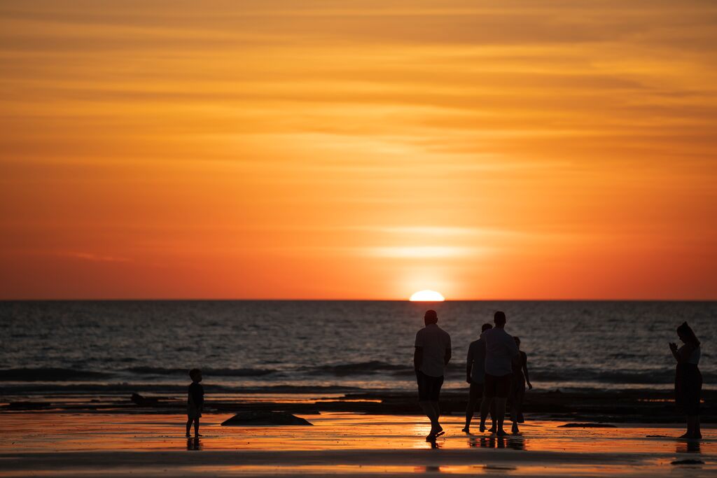 A group of people watching the sun set over the ocean at Cable Beach in Broome, in the Kimberley region of Western Australia.